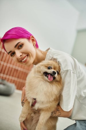 Photo for Delighted pet hotel worker embracing fluffy pomeranian spitz and smiling at camera, bonding and care - Royalty Free Image