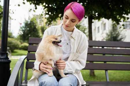 Photo for Park scene of purple-haired woman with pomeranian spitz relaxing on bench in park, outdoor leisure - Royalty Free Image