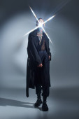 young man in black futuristic attire posing with spark of light on his face, fashion concept Longsleeve T-shirt #679132252