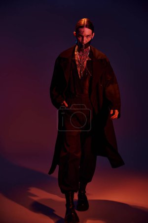 Photo for Good looking sexy man in futuristic outfit with laced stylish mask walking towards camera, fashion - Royalty Free Image