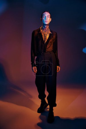 vertical shot of alluring man with accessories looking at camera with light on face, fashion concept