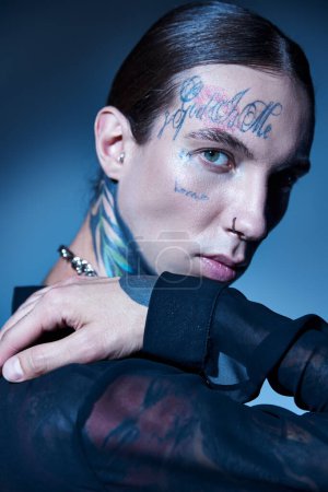 Téléchargez les photos : Séduisant jeune homme avec tatouages et perçage en chemise transparente regardant la caméra, concept de mode - en image libre de droit