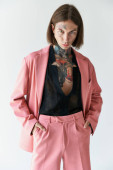handsome stylish male model with tattoos in pink blazer with hands in pockets, fashion concept hoodie #679133380