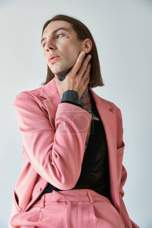 vertical shot of voguish young man in pink blazer and shorts with hand on neck looking away magic mug #679133630