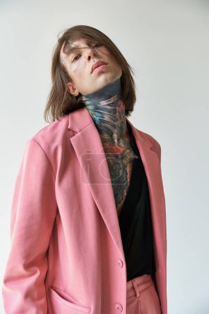 Foto de Tiro vertical de joven guapo en chaqueta rosa y camisa transparente mirando a la cámara, la moda - Imagen libre de derechos