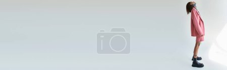 Téléchargez les photos : Élégant homme séduisant en tenue voguish regardant vers le haut sur fond gris, concept de mode, bannière - en image libre de droit