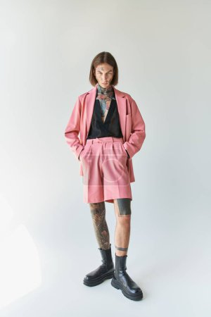 Foto de Tiro vertical de hombre con estilo de buen aspecto en chaqueta rosa y pantalones cortos mirando a la cámara, la moda - Imagen libre de derechos
