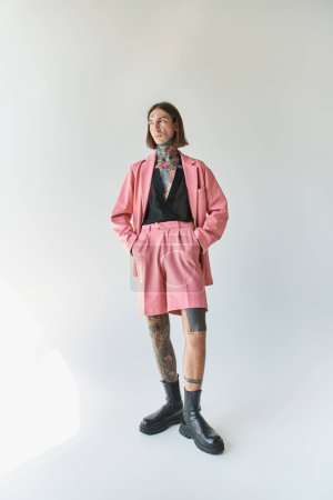 Téléchargez les photos : Plan vertical de beau jeune homme en blazer rose et short avec les mains dans les poches, mode - en image libre de droit
