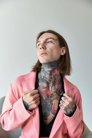 Téléchargez les photos : Plan vertical de jeune homme sexy avec des tatouages touchant le col de son élégant blazer rose, mode - en image libre de droit