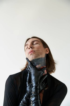 Téléchargez les photos : Plan vertical d'homme séduisant en chemise transparente avec les mains en gants de cuir sur le cou, la mode - en image libre de droit