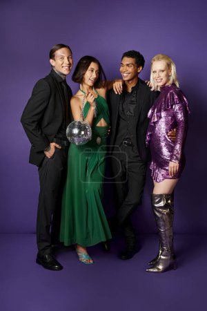 New Year 2024, group of joyful interracial friends in suits and dresses standing with disco ball