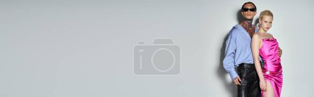 Téléchargez les photos : Couple à la mode en tenue de fête en regardant la caméra sur fond gris, bannière Nouvel An 2024 - en image libre de droit
