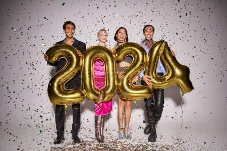happy interracial friends holding balloons with 2024 numbers near falling confetti, New Year party