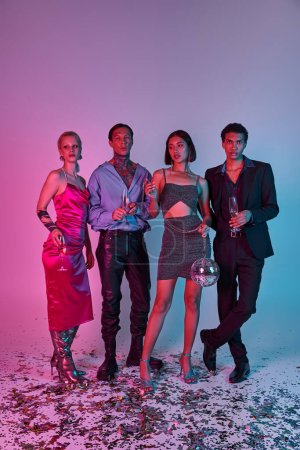 Foto de Grupo de amigos interracial sosteniendo copas de champán y bola disco sobre fondo rosa púrpura - Imagen libre de derechos