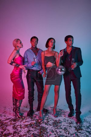cuatro amigos multiculturales sosteniendo copas de champán y bola disco sobre fondo rosa púrpura