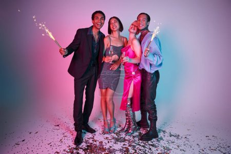 2024 New Year party, positive multiethnic friends holding sparklers and champagne on purple pink