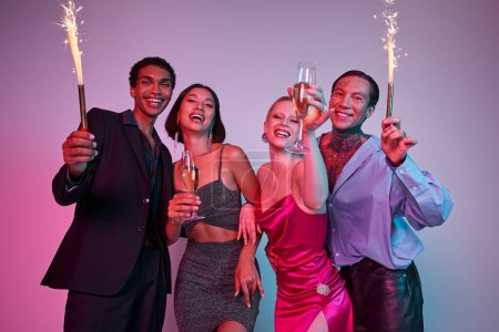 Photo for Merry Christmas and Happy New Year, joyous multiethnic friends holding sparklers and champagne - Royalty Free Image