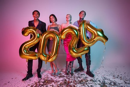 Frohes Neues Jahr, fröhliche multiethnische Freunde in festlicher Kleidung mit Luftballons mit 2024 Nummern