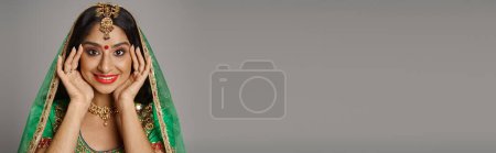 Téléchargez les photos : Joyeuse femme indienne avec point bindi et voile vert souriant à la caméra avec les mains près du visage, bannière - en image libre de droit