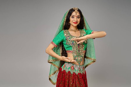 Téléchargez les photos : Attrayant jeune femme indienne avec point bindi posant avec les mains devant elle et regardant la caméra - en image libre de droit