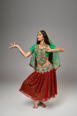 Photo for Vertical shot of indian attractive woman in traditional clothes gesturing while dancing actively - Royalty Free Image