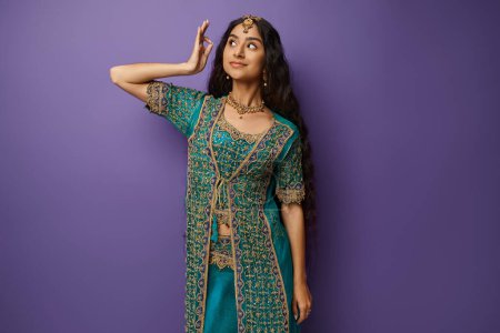 Photo for Attractive young indian woman in traditional blue sari with accessories posing on purple backdrop - Royalty Free Image