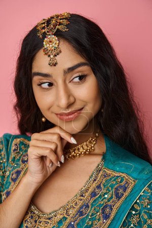 Photo for Vertical shot of attractive indian woman in blue sari with accessories posing with hand on chin - Royalty Free Image