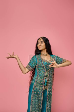 Photo for Joyful attractive indian woman in traditional blue sari posing on pink background and looking away - Royalty Free Image