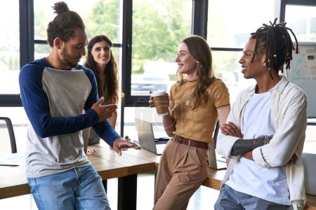 african american man talking to woman with paper cup during meeting with creative multiethnic team