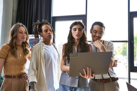 nachdenkliches multiethnisches Team schaut auf Laptop, während es im Büro an einem neuen Geschäftsprojekt arbeitet