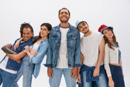 cheerful multiethnic friends posing near african american man standing with closed eyes on grey