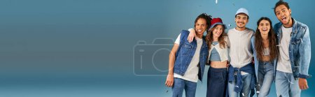 Photo for Happy interracial friends in stylish casual wear under sparkling confetti rain on blue, banner - Royalty Free Image