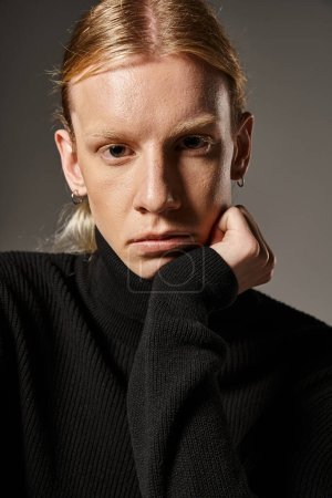 portrait of young non binary person in black turtleneck with ponytail looking at camera, fashion