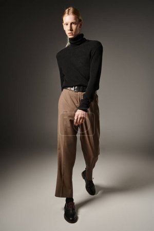 Photo for Vertical shot of young non binary person in black turtleneck and brown pants looking at camera - Royalty Free Image
