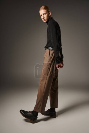 Photo for Attractive non binary model in elegant attire with ponytail posing with arms behind back, fashion - Royalty Free Image
