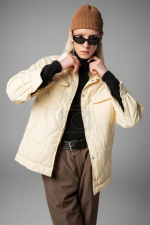 modelo joven no binario en chaqueta de invierno tocando cuello de cuello alto negro, concepto de moda