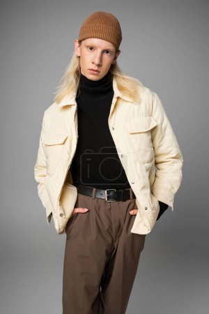 vertical shot of good looking non binary model in stylish winter attire posing and looking at camera