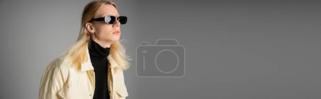stylish androgynous person in winter jacket with sunglasses looking away, fashion concept, banner