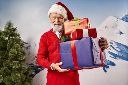 weißer bärtiger Weihnachtsmann hält Geschenke in der Hand und lächelt in die Kamera vor verschneiter Kulisse, Winterkonzept