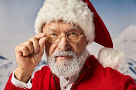 Porträt des Weihnachtsmannes, der seine Brille berührt und direkt in die Kamera blickt, Frohe Weihnachten