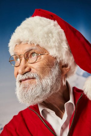 Weißbärtiger alter Mann im Weihnachtsmann-Festtagskostüm mit Brille und wegschauendem Blick, Winterkonzept