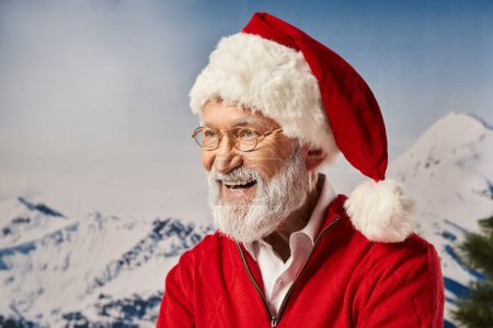 cheerful man in Santa red costume and glasses smiling happily with snowy backdrop, winter concept