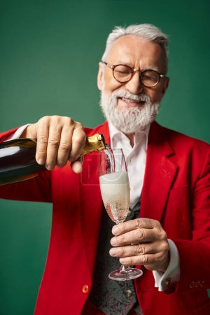 cheerful elegant Santa Claus pouring champagne into flute glass and smiling happily, winter concept