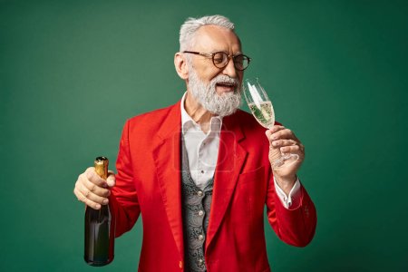 classy jolly Santa Claus enjoying champagne and smiling on dark green backdrop, winter concept