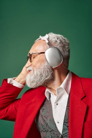 dreamy Santa with glasses and beard posing in profile with headphones with closed eyes, winter