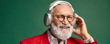 cheerful man dressed as Santa Claus with beard and headphones smiling at camera, winter, banner