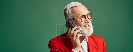 alegre elegante Santa en traje rojo con clase hablando por teléfono y mirando hacia otro lado, concepto de invierno, bandera
