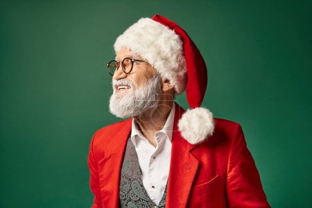 alegre elegante Santa en sombrero navideño y gafas sonriendo y posando en perfil, concepto de invierno