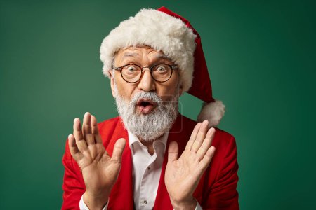 astonished Santa in christmassy hat and glasses gesturing with slightly open mouth, winter concept