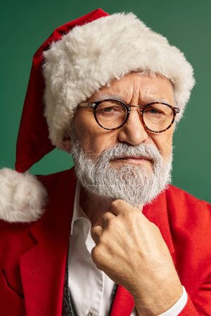 Senkrechte Aufnahme von ernstem Weihnachtsmann mit Weihnachtsmütze und Brille, der in die Kamera schaut, Weihnachtskonzept